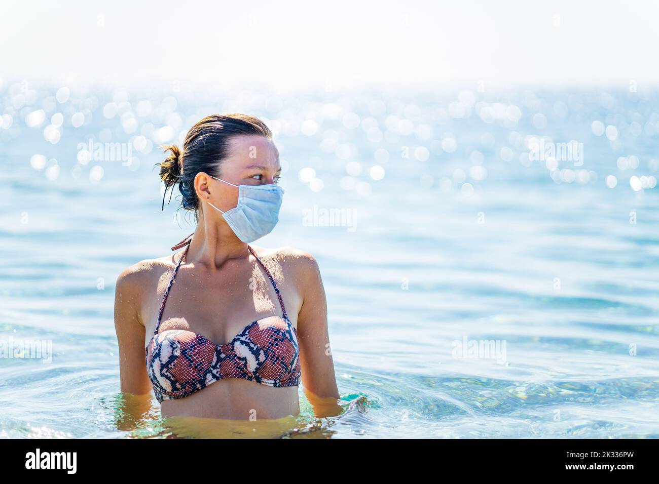 femme paranoïaque nageant sur l'eau avec un masque sur le visage le jour ensoleillé Banque D'Images