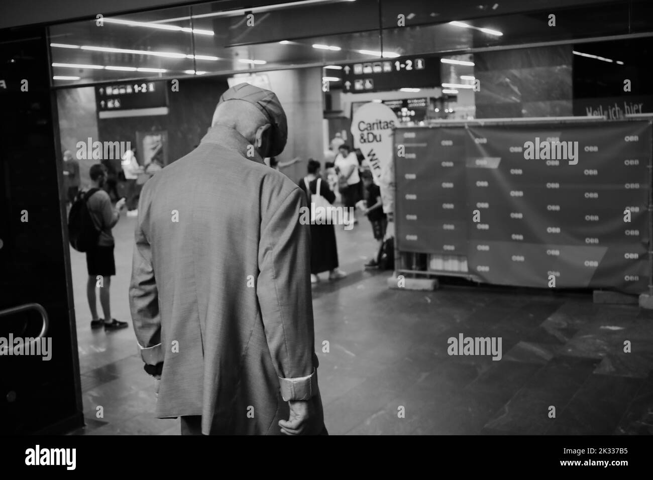 Photo en échelle de gris d'un vieil homme entrant dans la gare urbaine Banque D'Images