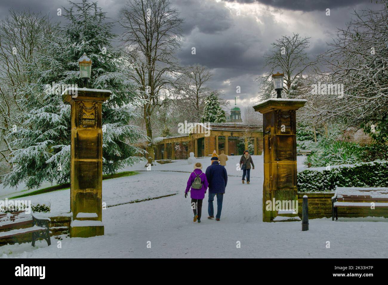 Touristes marchant dans les jardins de la vallée pendant un froid décembre matin avec la neige couvrant le sol et les arbres, Harrogate, Yorkshire. ROYAUME-UNI. Banque D'Images