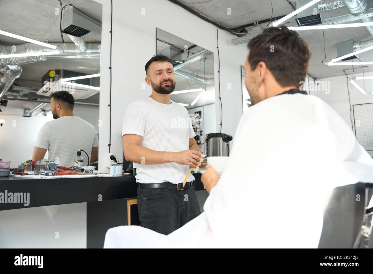 Coiffeur incroyable fournissant le meilleur service à la clientèle au visiteur de salon de coiffure Banque D'Images