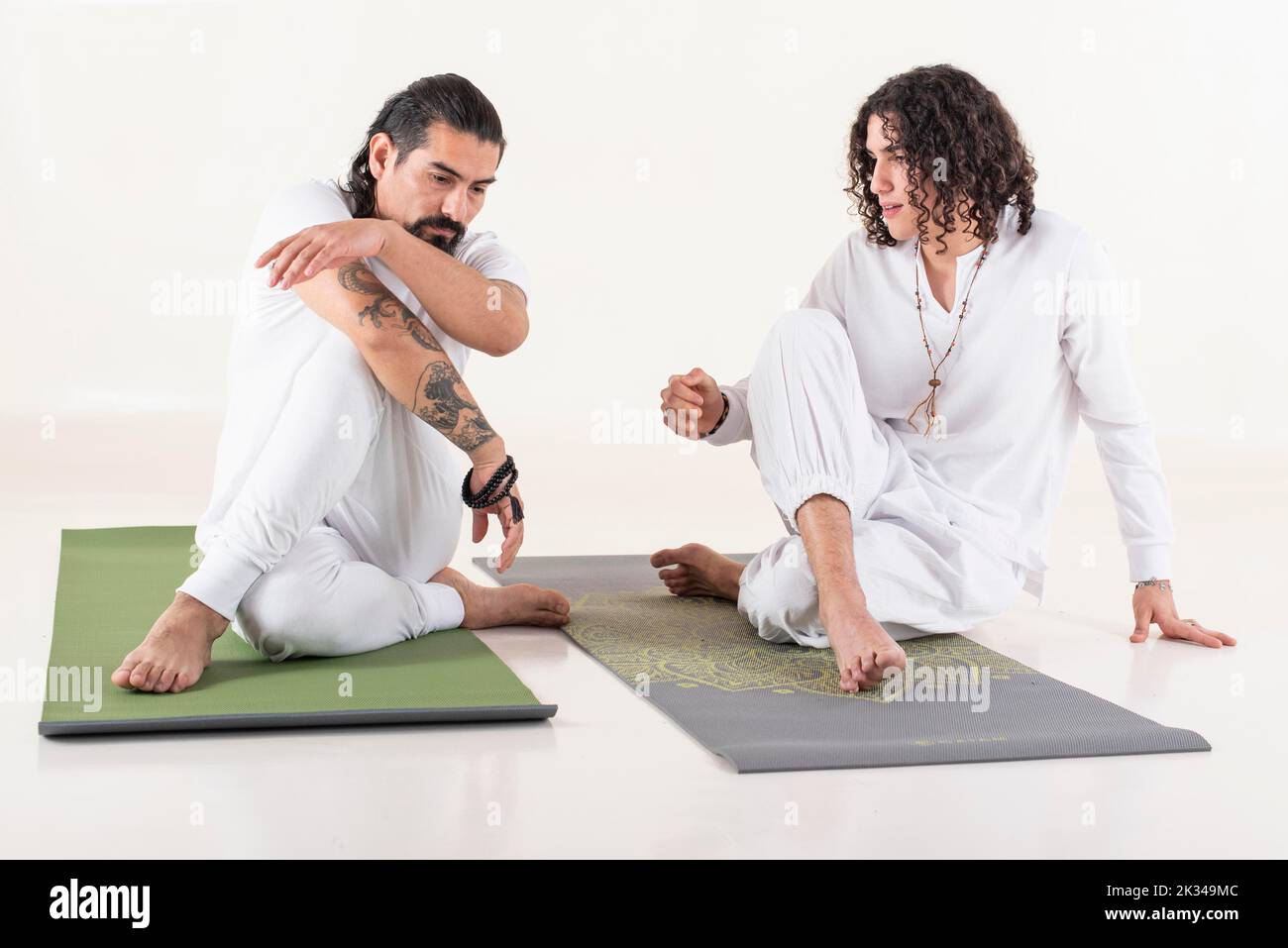 Un instructeur de yoga enseigne le yoga à un jeune homme. Les deux sont vêtus de vêtements de yoga blancs. Vue avant Banque D'Images