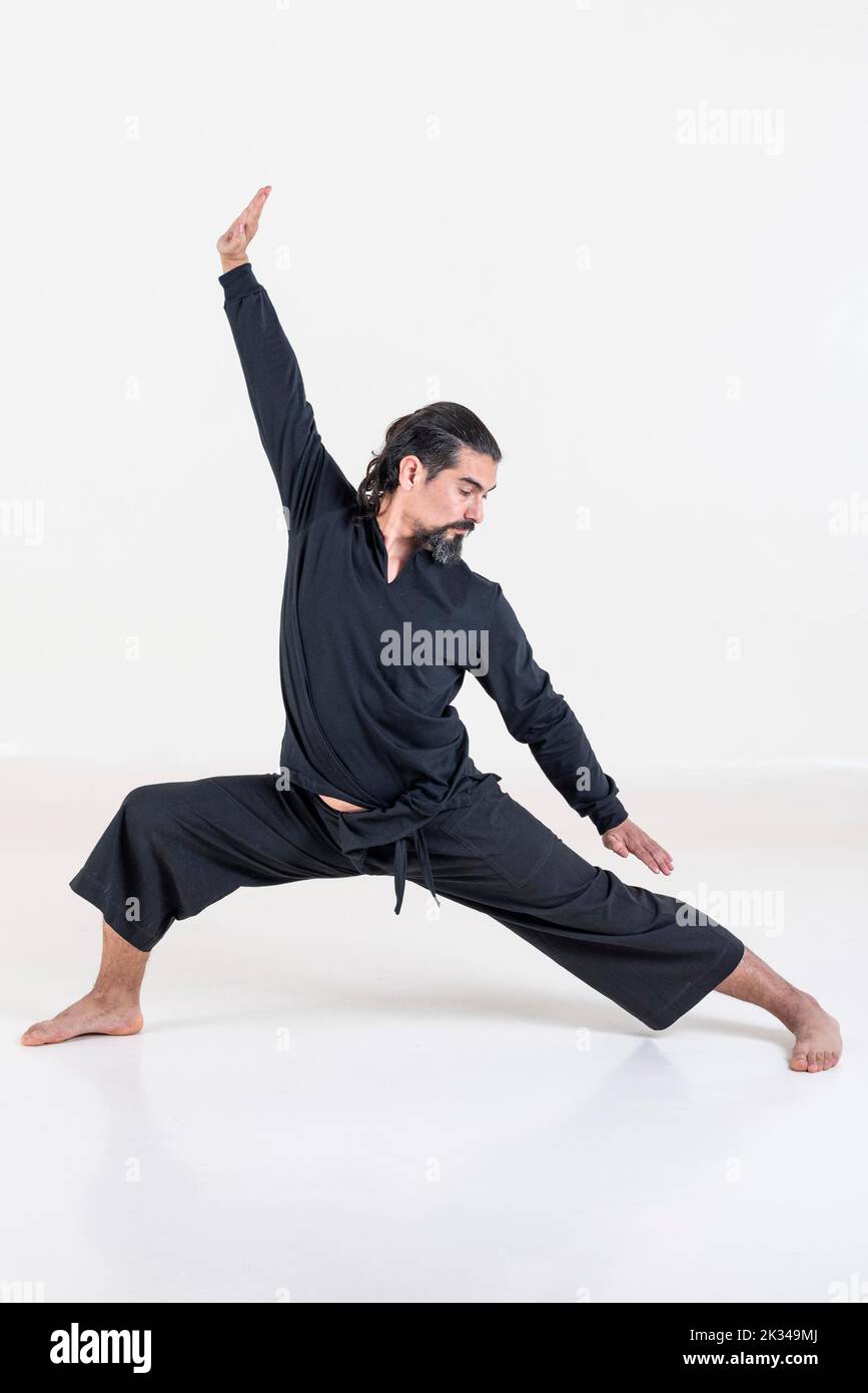 Un homme vêtu de noir faisant du yoga sur fond blanc. Prise de vue en studio Banque D'Images