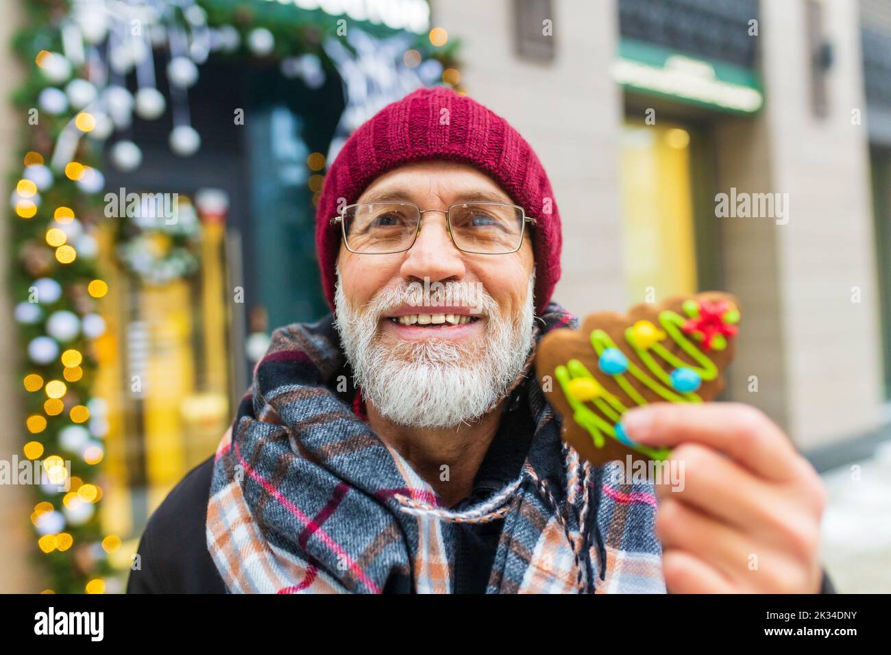 joyeux homme montrant le biscuit vert doux arbre de noël forme en plein air dans le marché d'hiver Banque D'Images