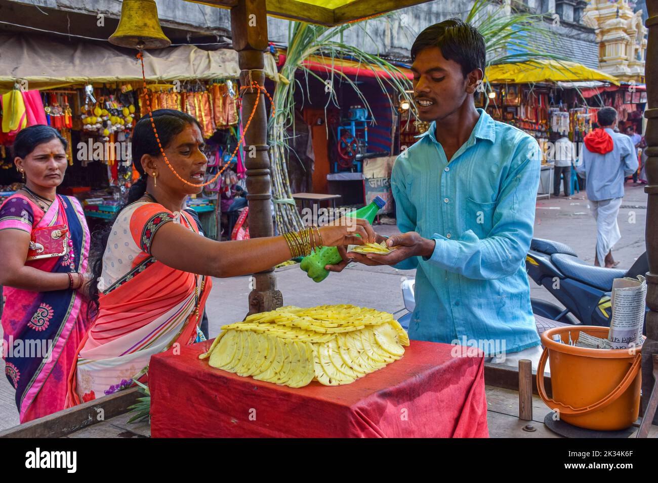 Tuljapur,Inde- 19 décembre 2019; photo de l'homme de 25 à 30 ans qui vend des tranches d'ananas frais juteux à une cliente de la zone de marché.sl Banque D'Images