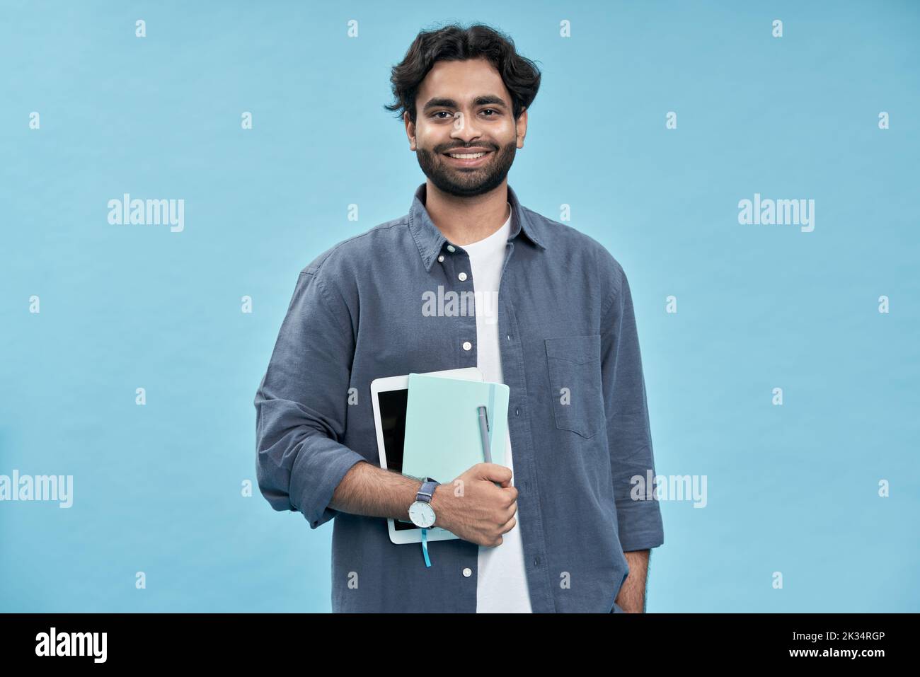 Jeune homme arabe souriant étudiant debout isolé sur fond bleu. Banque D'Images