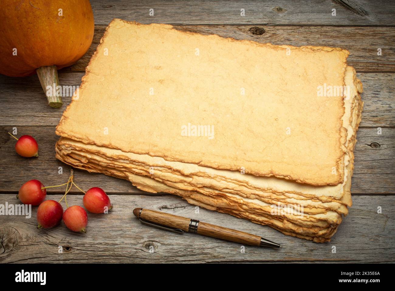 pile de papier vierge fait à la main avec des bords rugueux contre le bois rustiques abîmé avec des pommes de citrouille et de crabe, thème des fêtes d'automne Banque D'Images