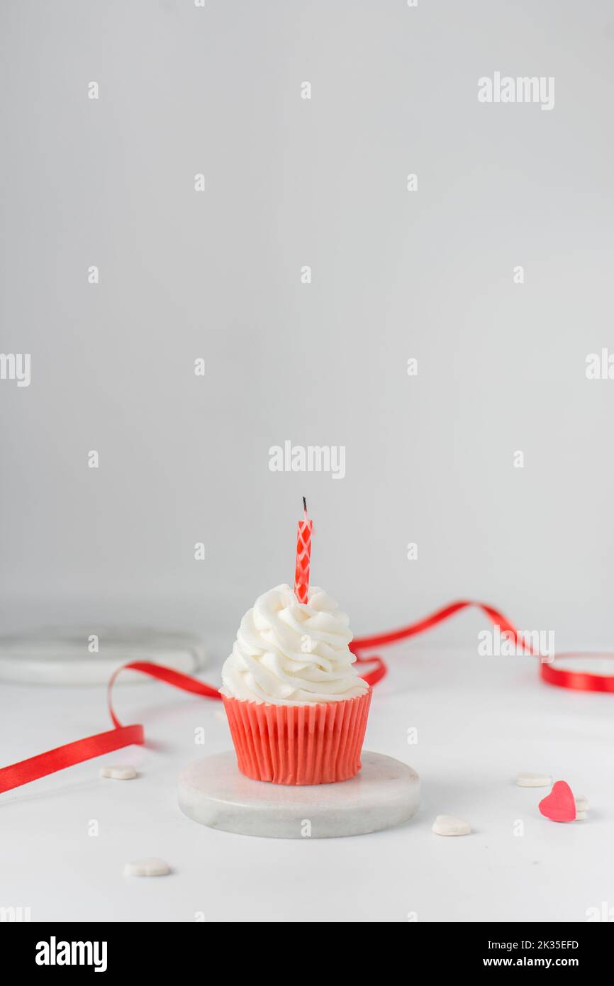 Cupcake blanc et rouge avec une bougie sur le dessus, glaçage blanc sur un cupcake rouge, cupcakes de jour de Saint-Valentin Banque D'Images