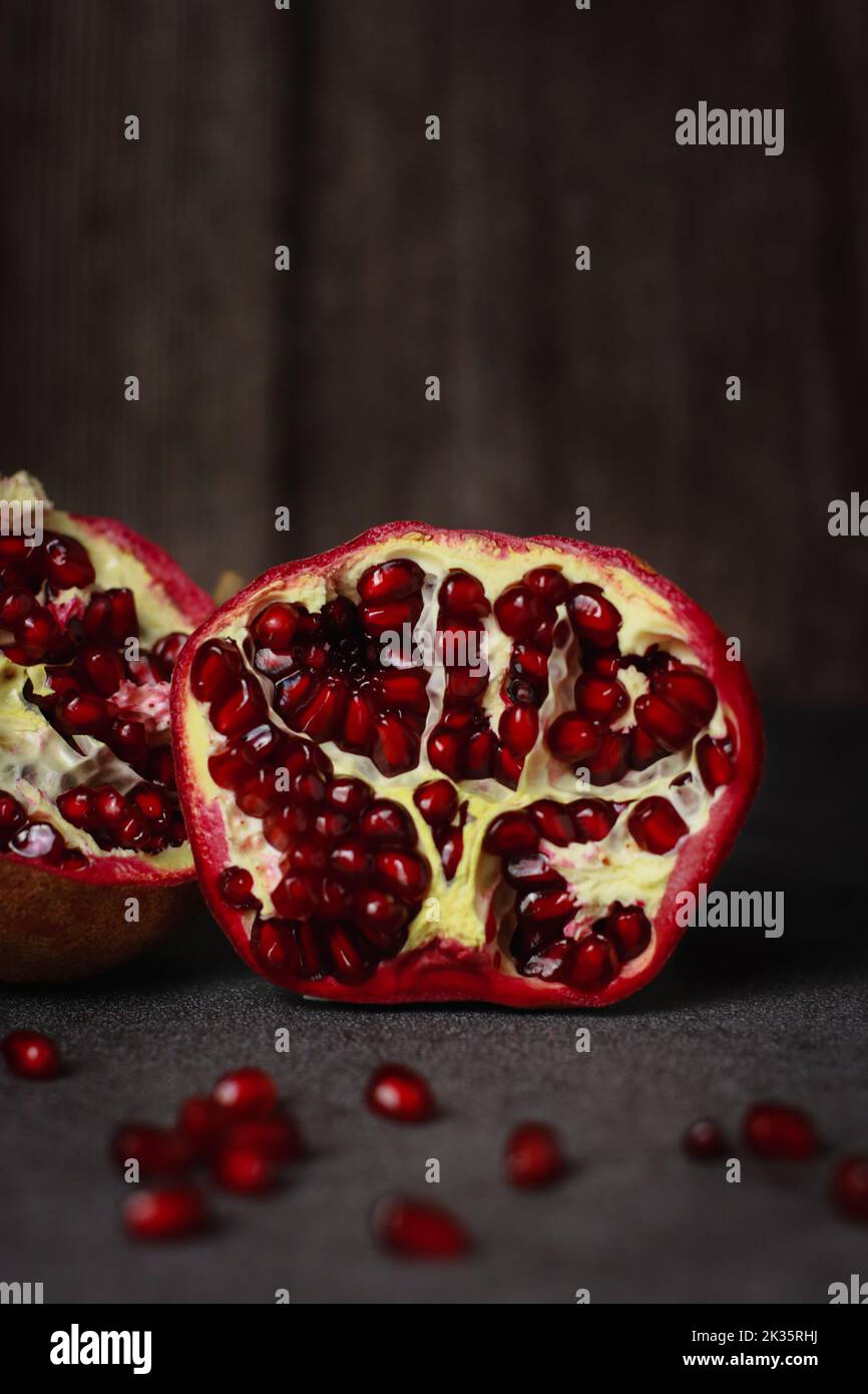 gros plan d'une grenade coupée sur une table grise et un arrière-plan sombre en bois Banque D'Images