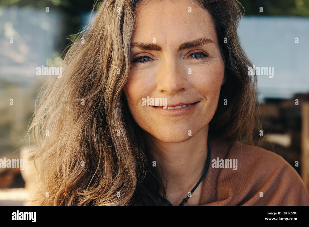 Portrait d'une femme mûre souriant à l'appareil photo tout en portant un collier en cristal. Femme âgée méditant et pratiquant l'auto-guérison à la maison. Heureux Banque D'Images