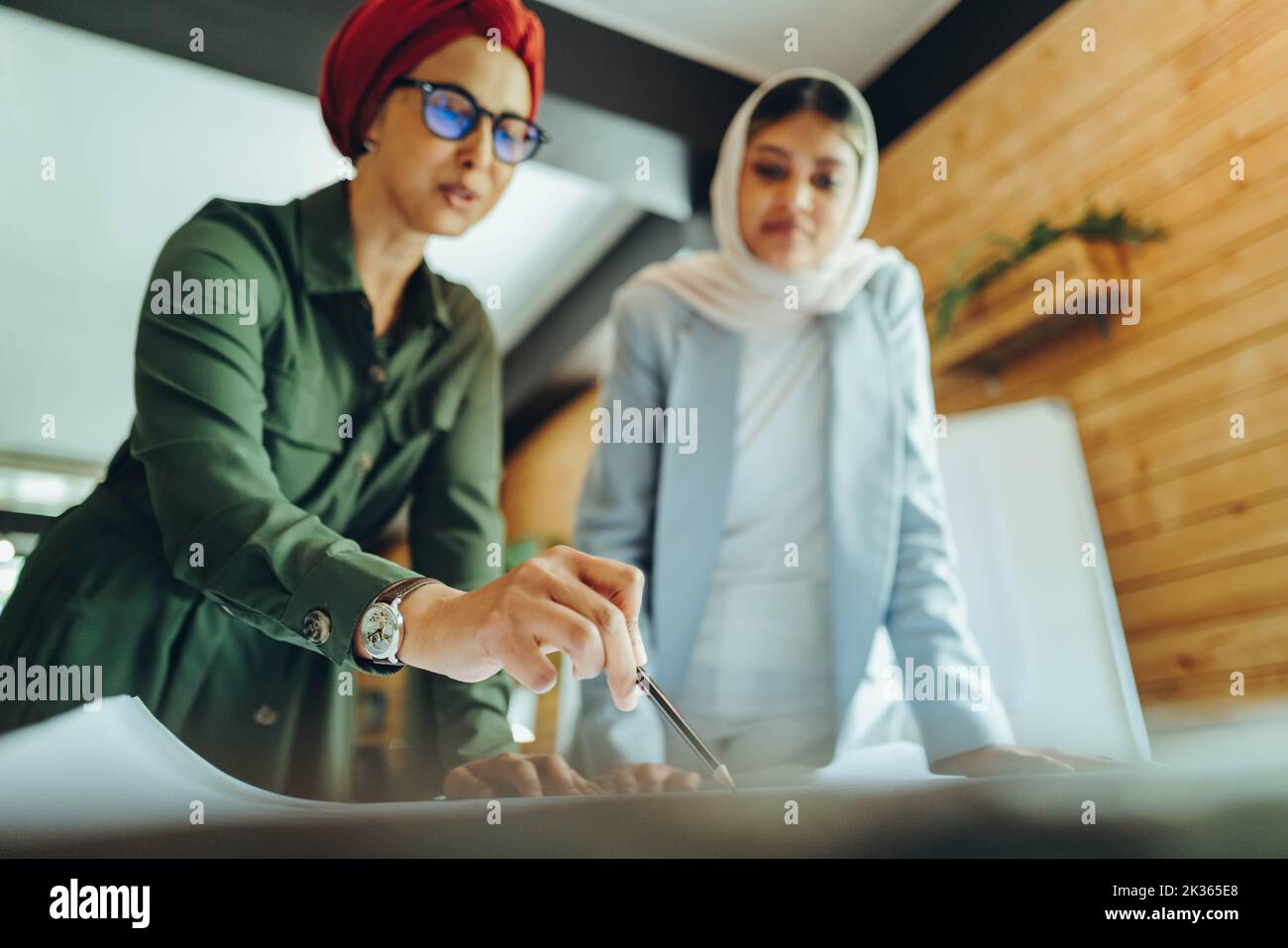Architectes musulmans créatifs travaillant sur des plans-plans dans un bureau moderne. Deux femmes d'affaires planifiant un nouveau projet novateur. Deux femmes designers Banque D'Images