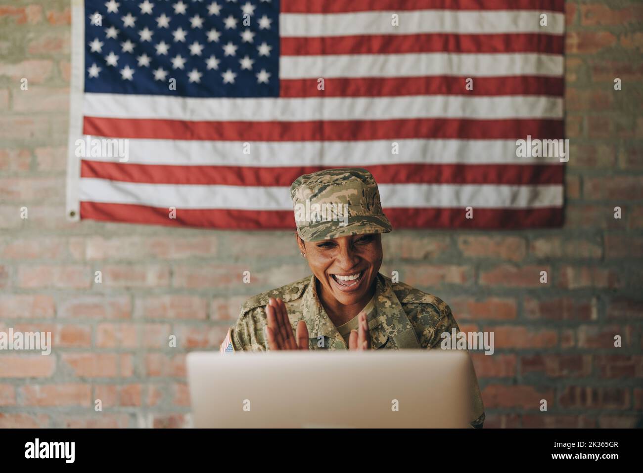 Une femme heureuse sourit joyeusement tout en visiophonie à sa famille sur un ordinateur portable. Une militaire américaine qui communique avec ses proches tout en s'assurant Banque D'Images