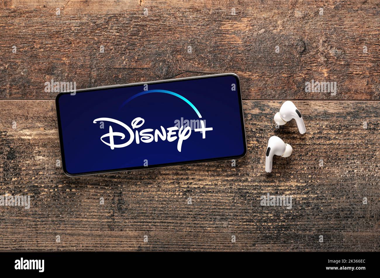 Etats-Unis, NEW YORK 22 septembre 2022 : gros plan du téléphone avec le nouveau logo Disney et des écouteurs modernes sur une ancienne table en bois. Disney plus est bien connu dans le monde entier Banque D'Images