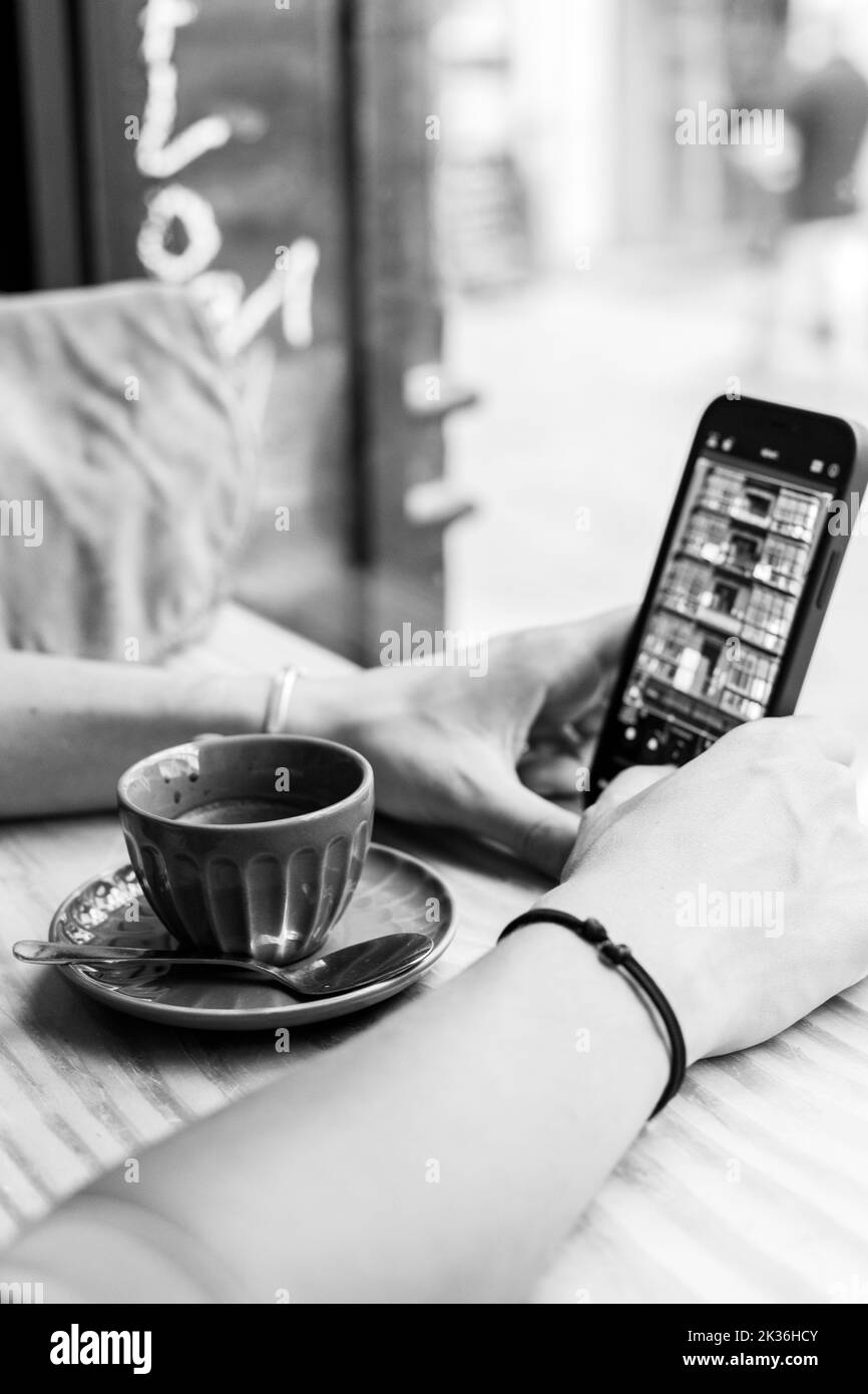 Femme sur son téléphone éditant une image dans un café. Banque D'Images