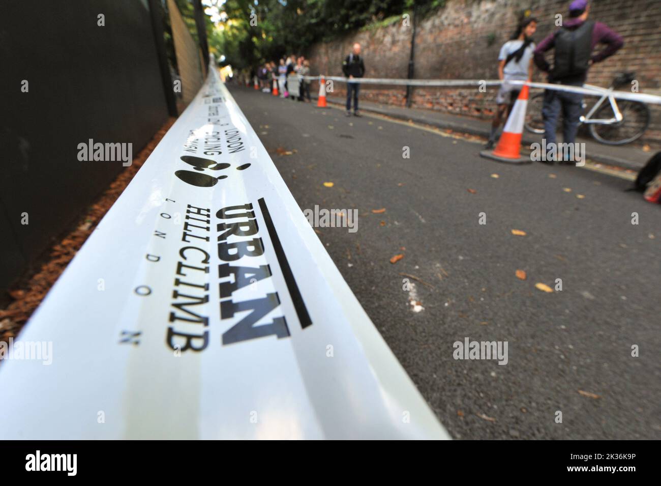 Bande périmétrique au cours de la course de rue Urban Hill Climb organisée par la London Cycling Campaign, parrainée par Osbornes Law. L'événement est une course à plat dans la rue la plus raide de Londres et, en plus des catégories d'âge et de sexe, des compétitions pour les vélos pliants et cargo. Swain’s Lane est l’ascension la plus célèbre et la plus célèbre de Londres. La voie est une section de route extrêmement raide, située entre Hampstead Heath et Highgate Cemetery avec un gradient qui est en moyenne de 9% sur 0,6km, mais augmente à 14% près du sommet de l'ascension. Banque D'Images