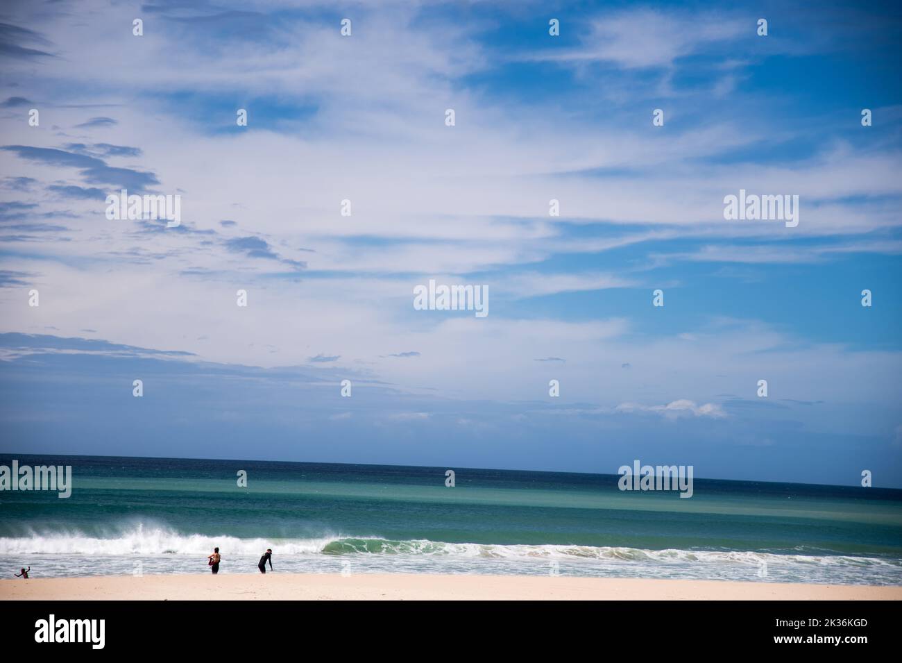Magnifique océan pittoresque multicolore avec brise-roches, ciel bleu avec nuages texturés surplombant la plage de sable fin Banque D'Images