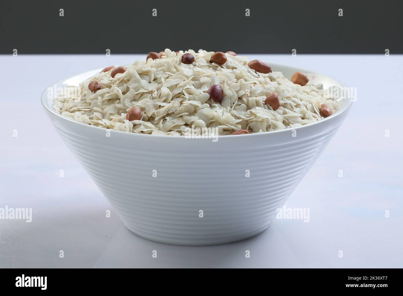 Riz aplati cru ou flocons de riz épais ou fins pour les en-cas Namkeen Chivda ou Aloo Poha pour le petit déjeuner indien, servis dans un bol. Banque D'Images