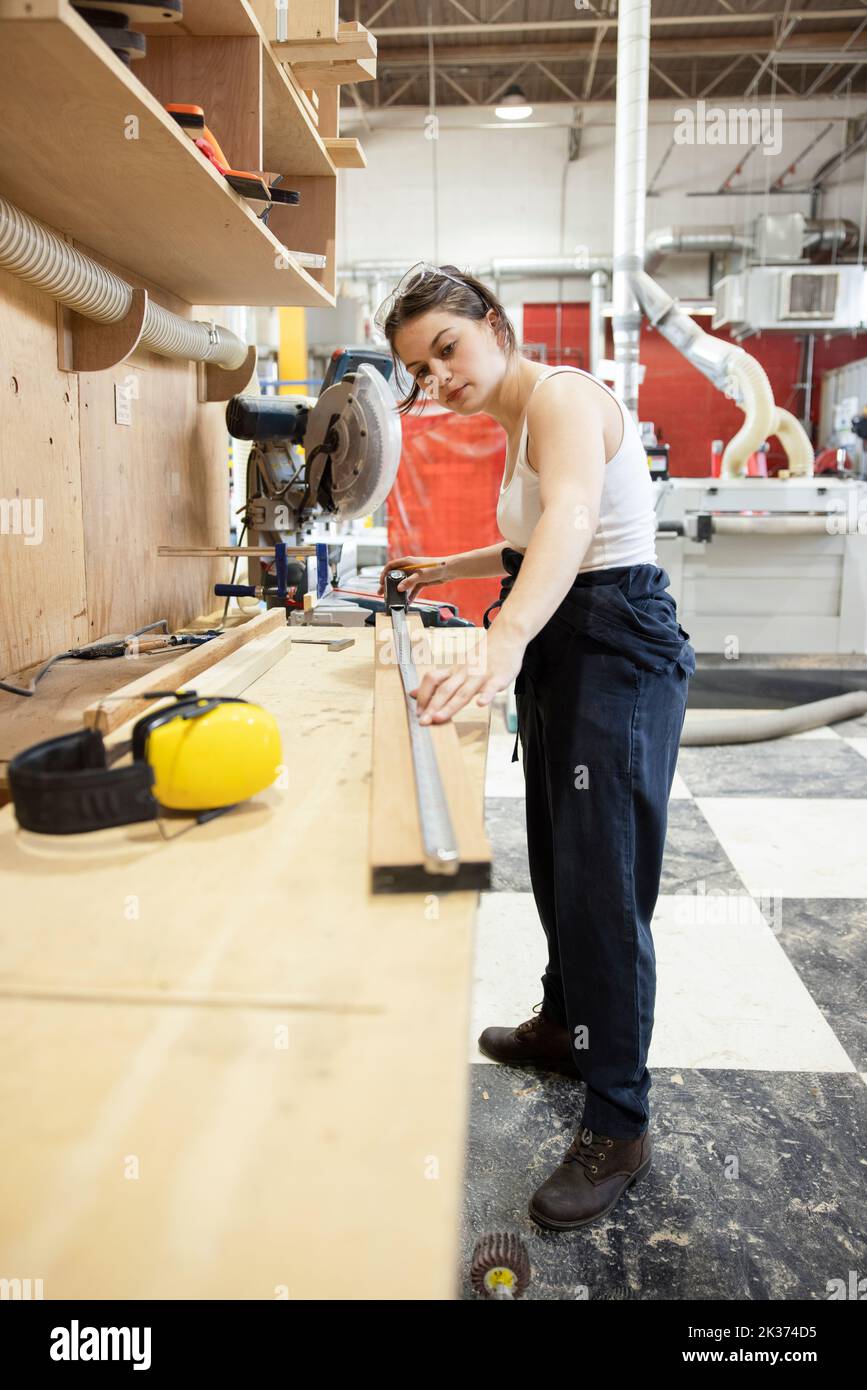 Femme bois mesurant le bois dans l'atelier Banque D'Images