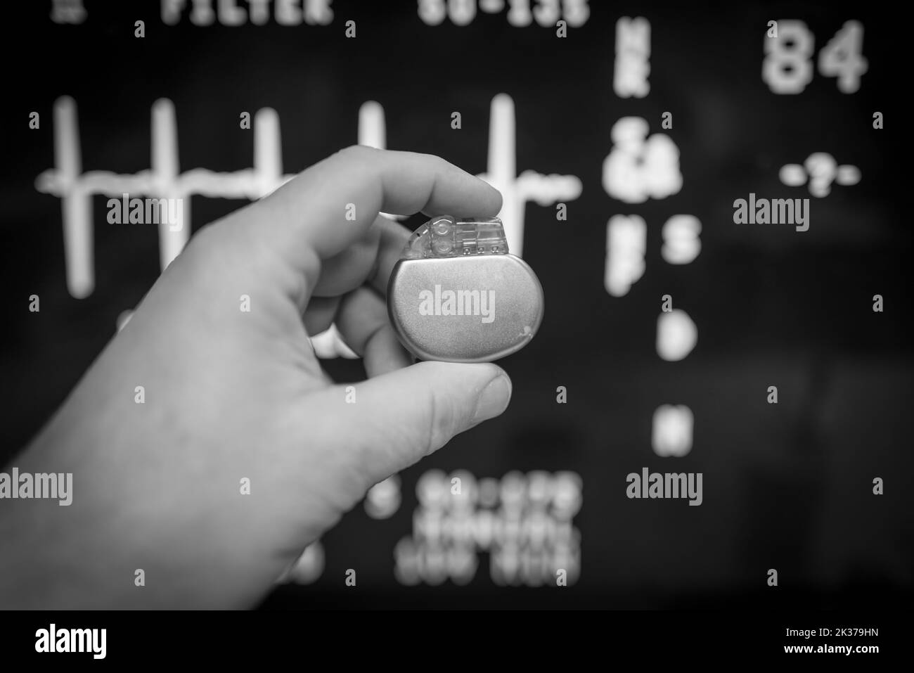 Un stimulateur cardiaque implantable est maintenu devant un moniteur ECG Banque D'Images