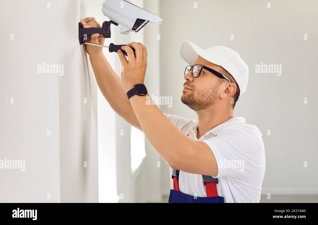 Technicien installant une caméra de vidéosurveillance moderne à l'intérieur d'une maison ou d'un immeuble de bureaux Banque D'Images