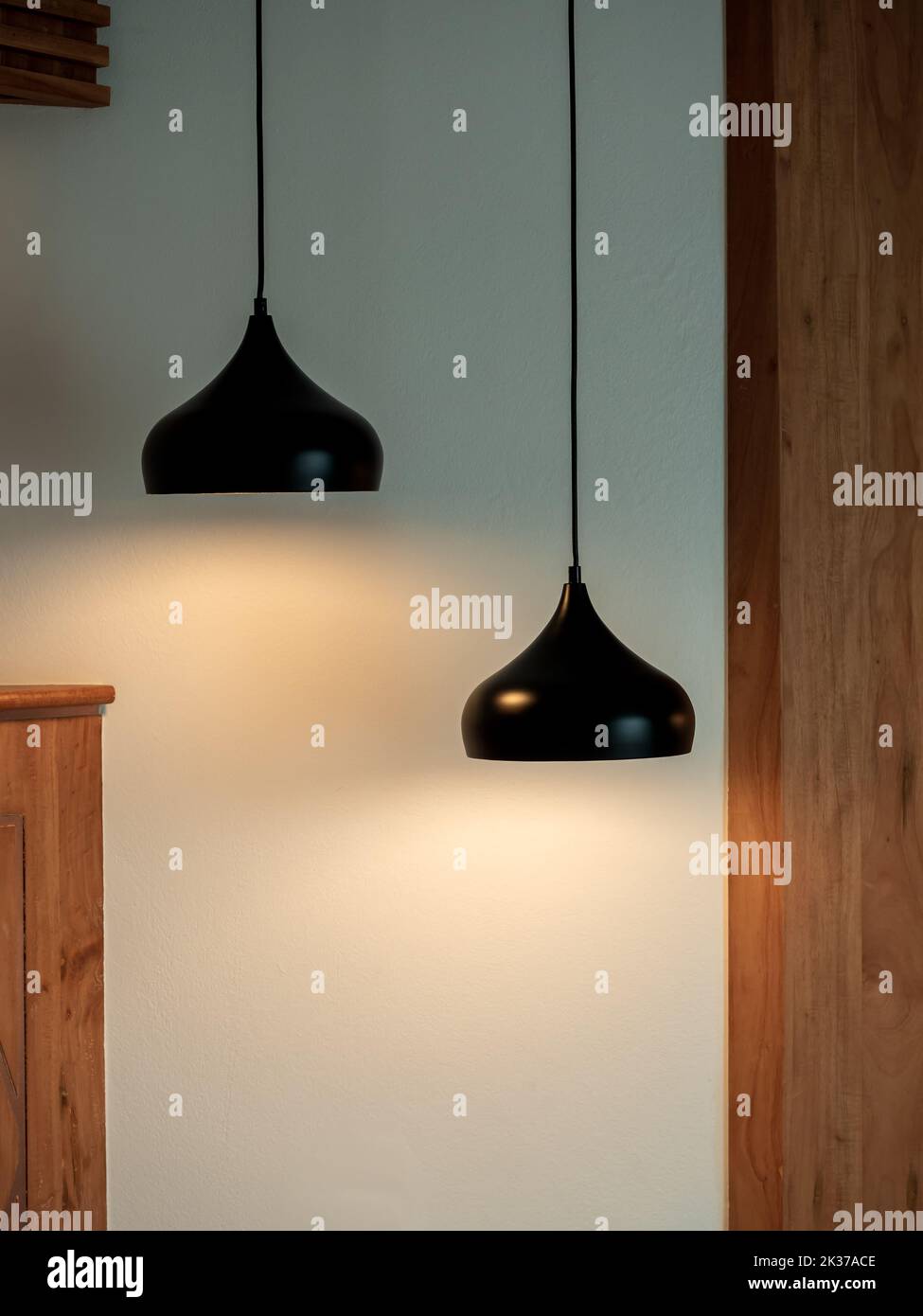 Deux plafonniers dans la pièce sombre. Deux lampes suspendues ou plafonniers ronds décorés comme un pas sur un mur blanc et en bois, de style vertical. Banque D'Images