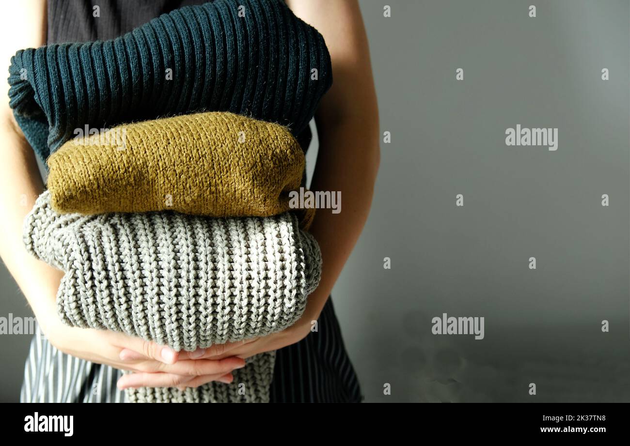 femme tenant dans sa pile de chandails chauds en laine et de cardigans Banque D'Images