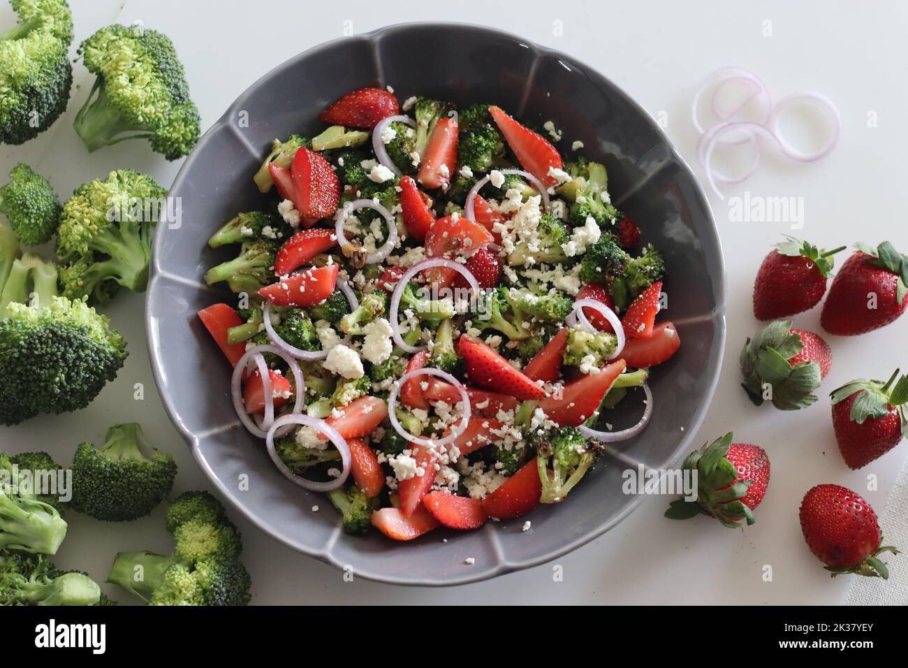 Brocoli au fromage feta et tranches de fraises fraîches. Des bouquets de brocoli sautés saupoudrés de fromage féta émietté et de fraises fraîches Banque D'Images