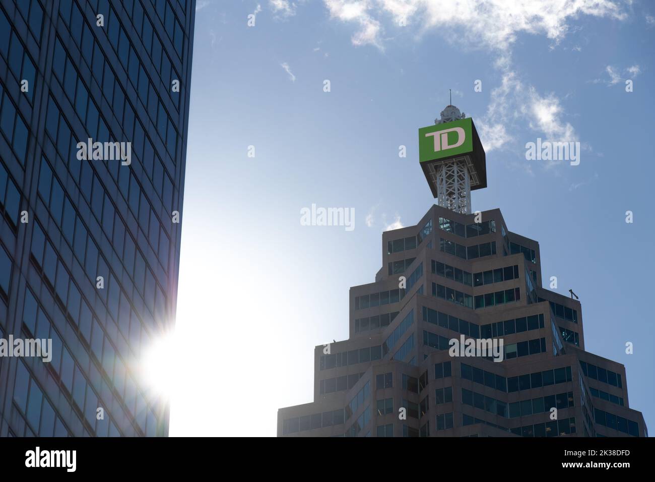 Le soleil brille à travers les édifices en hauteur du quartier financier de Toronto, tandis qu'un panneau TD éclairé est visible au sommet de la tour TD. Banque D'Images