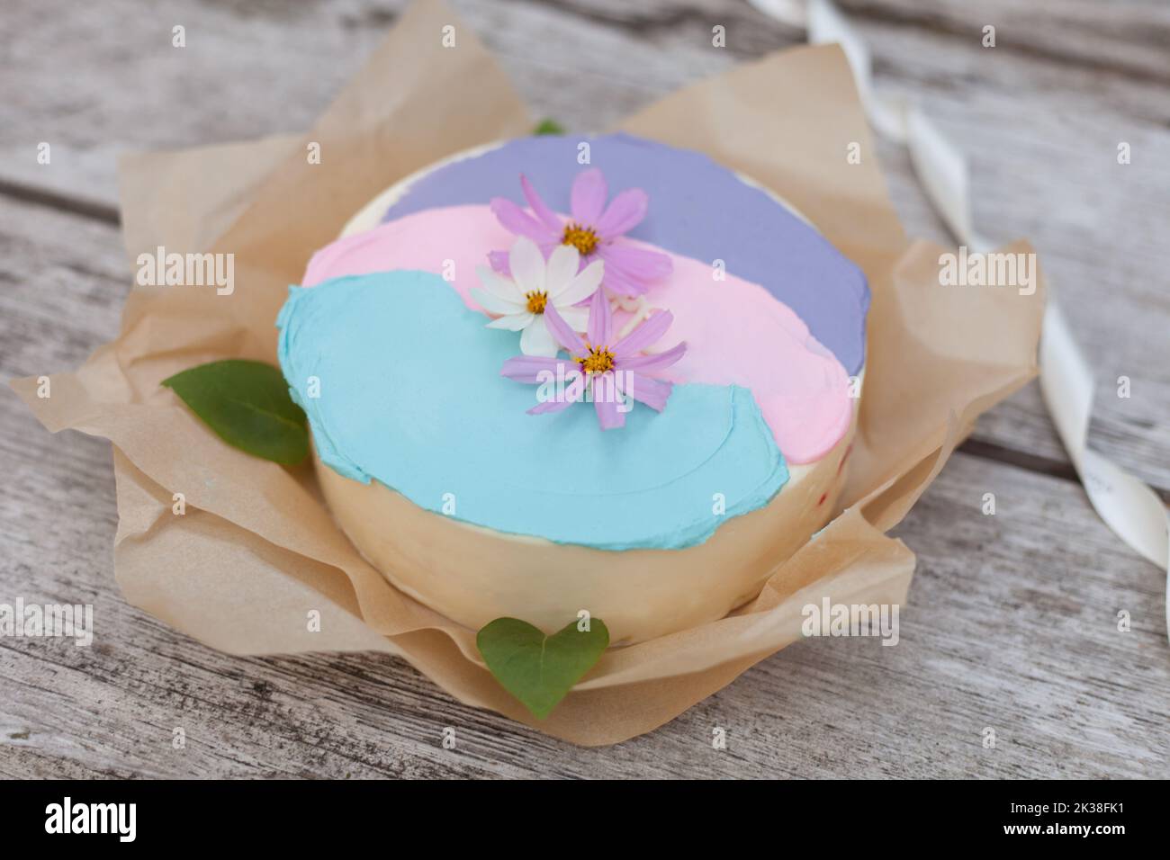 gâteau rose aux fleurs. délicate tarte beige décorée de cosmos sur fond de bois Banque D'Images