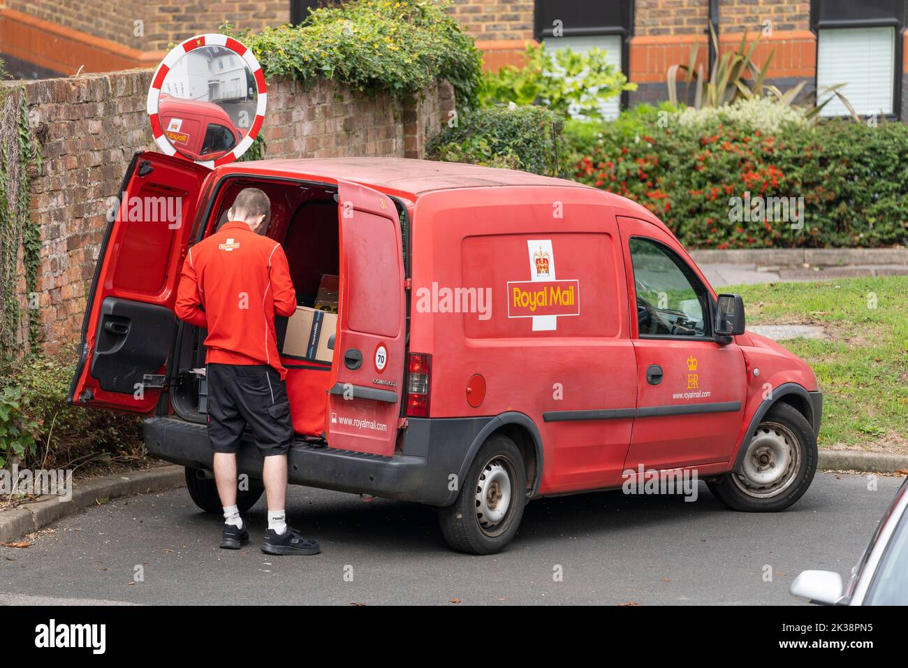 Royal Mail Group : camion de livraison rouge et homme de poste. Angleterre, Royaume-Uni. Concept - marque Royal Mail, service postal, collecte de courrier, livraison de colis Banque D'Images