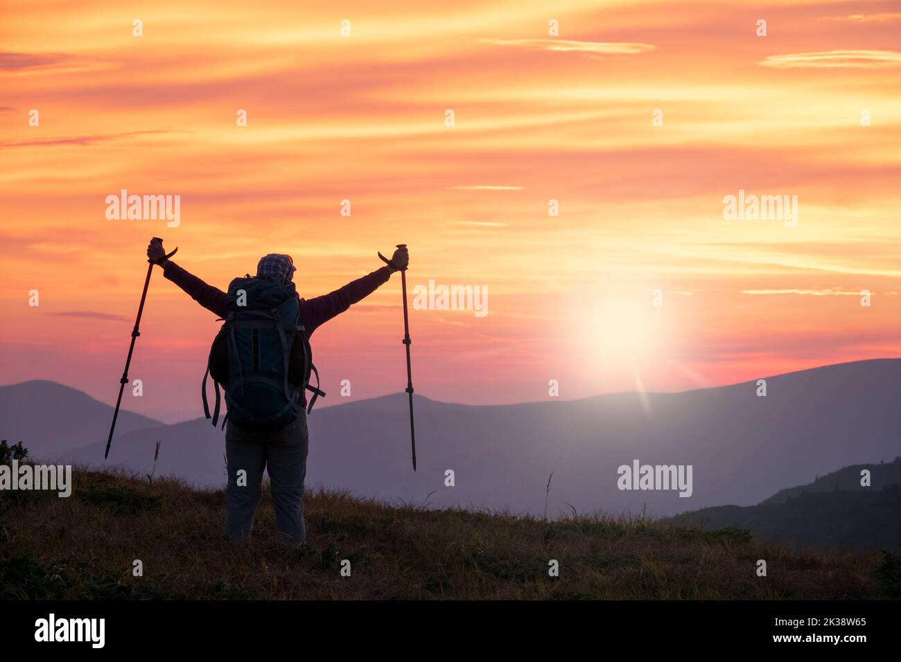 Le randonneur sur le sommet de la montagne accueille le lever du soleil avec les bras levés Banque D'Images