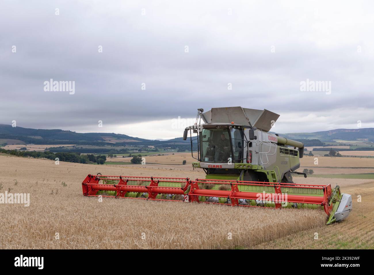 Une moissonneuse-batteuse récolte de l'orge lors d'une soirée en fonte avec une vue sur le paysage environnant Banque D'Images