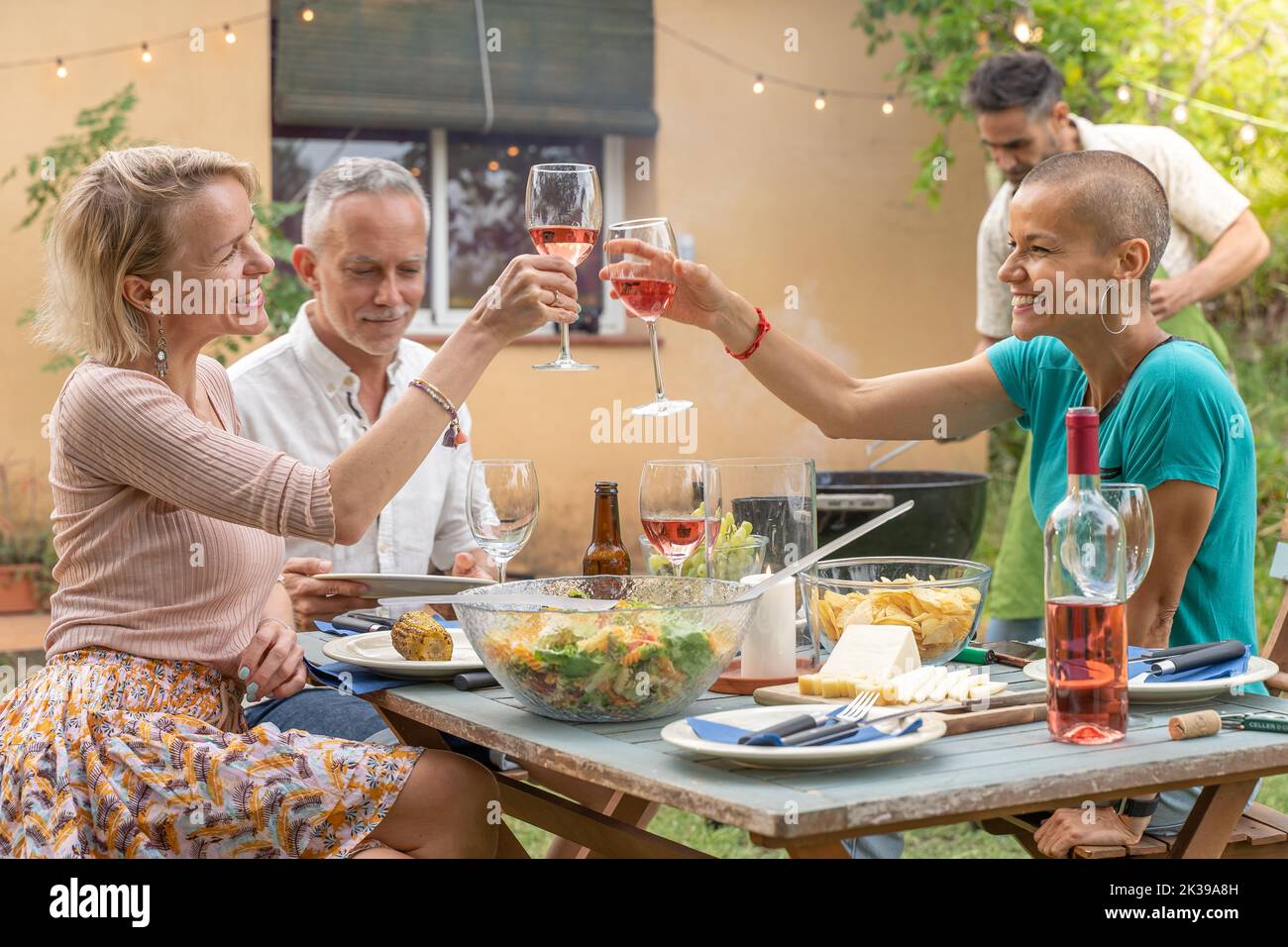 Des amis de groupe qui se coutent avec un grand sourire autour de la table dans le patio de la maison. Banque D'Images