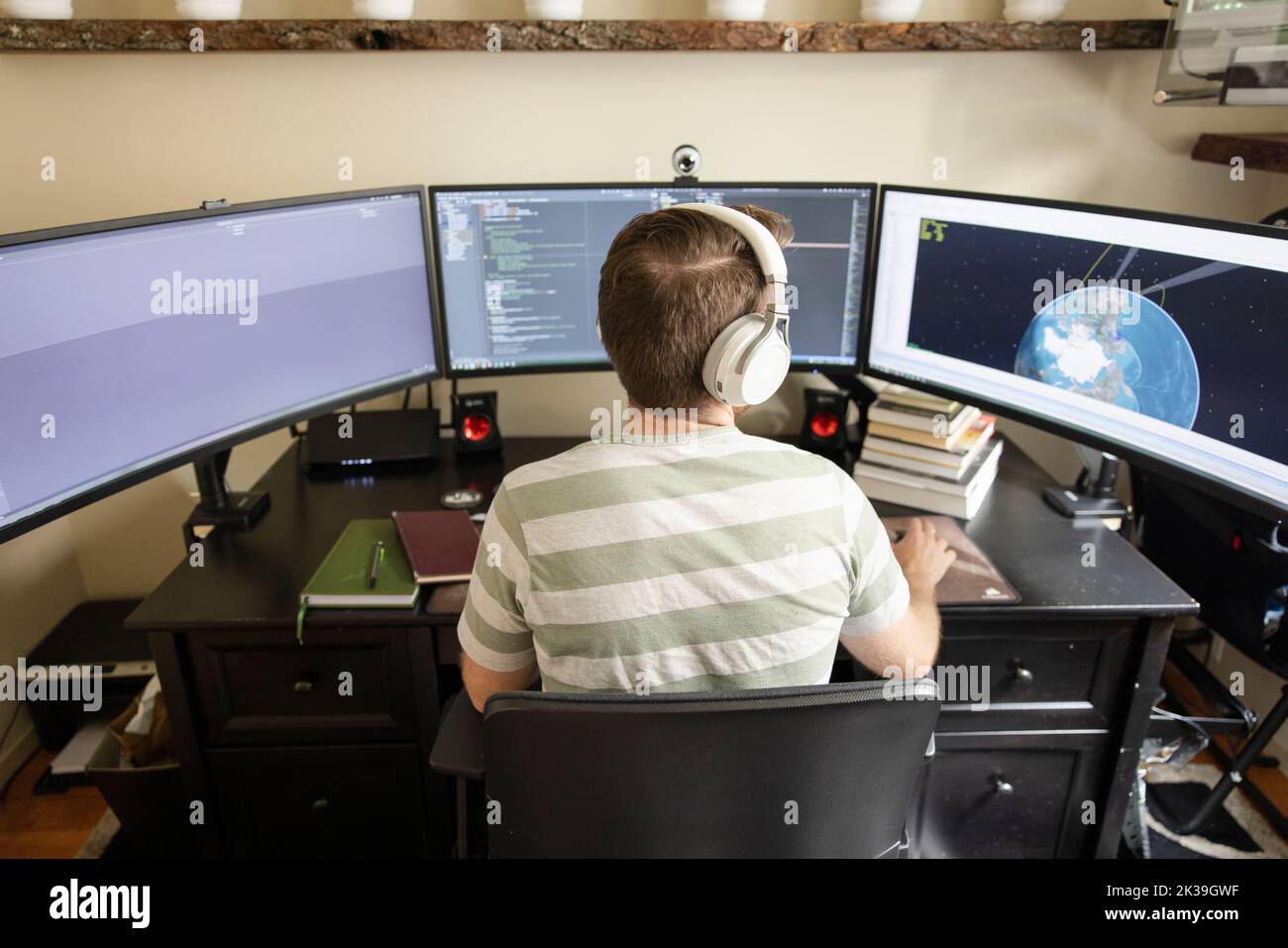 Homme avec un casque travaillant à domicile sur des moniteurs d'ordinateur Banque D'Images
