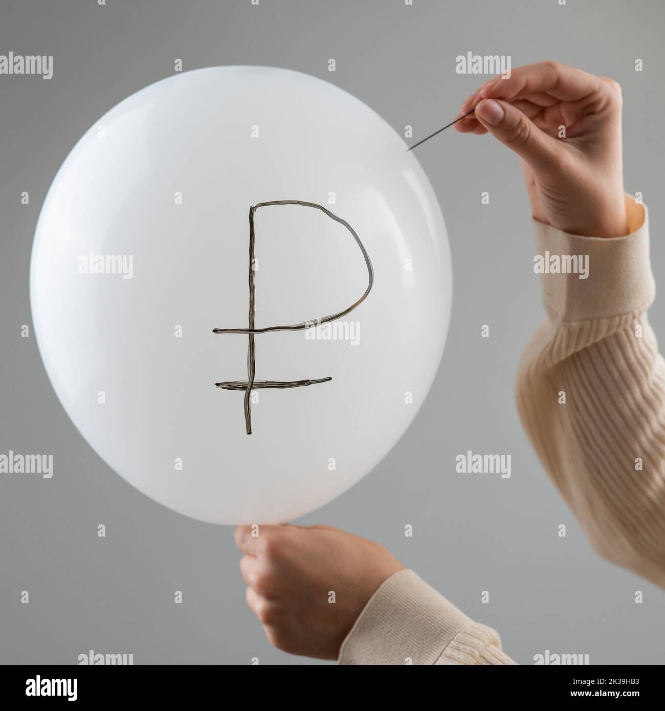 Une femme caucasienne fait apparaître un ballon avec une inscription rouble et une aiguille. Banque D'Images
