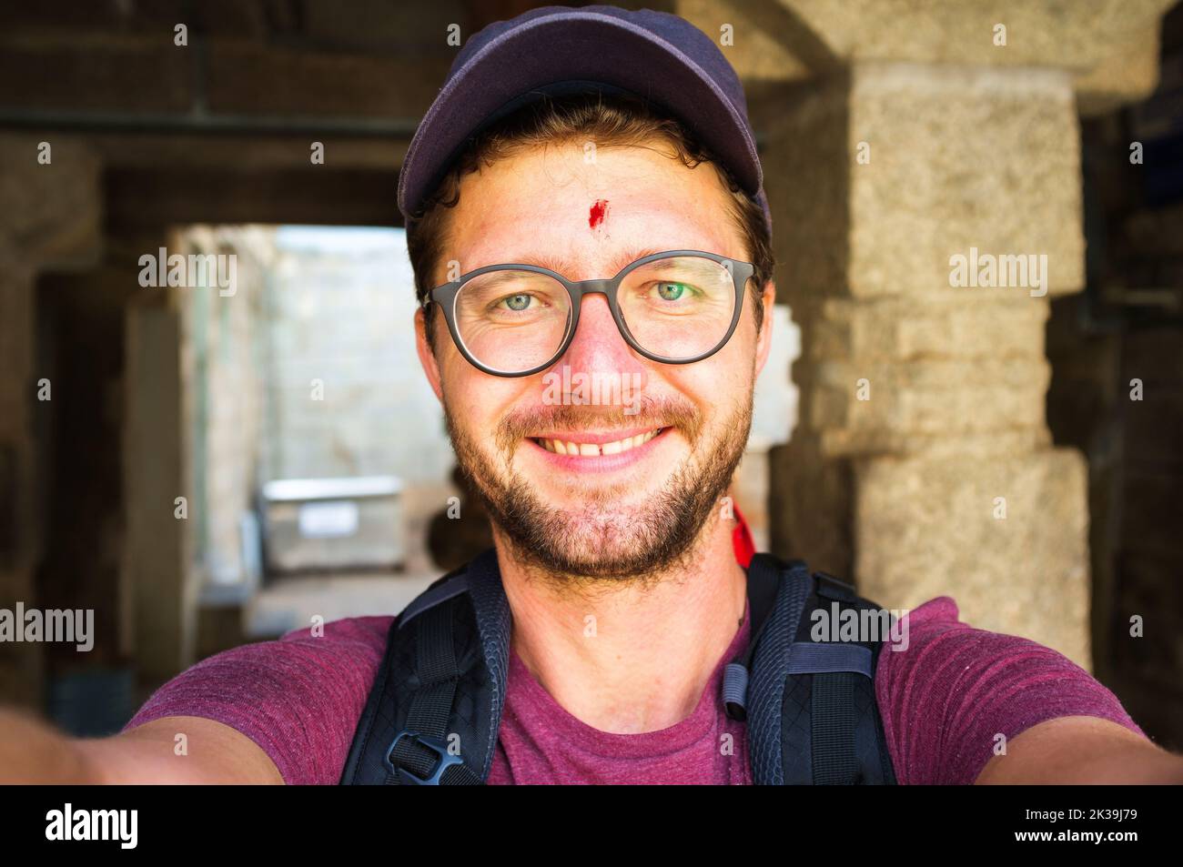 Un jeune homme avec un bindi rouge point portant un capuchon de lunettes et un sac à dos posant pour un selfie Banque D'Images