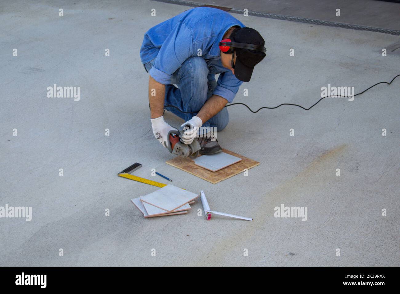 Image d'un ouvrier de la construction coupant des carreaux avec une meuleuse d'angle. Je travaille comme un tiler Banque D'Images