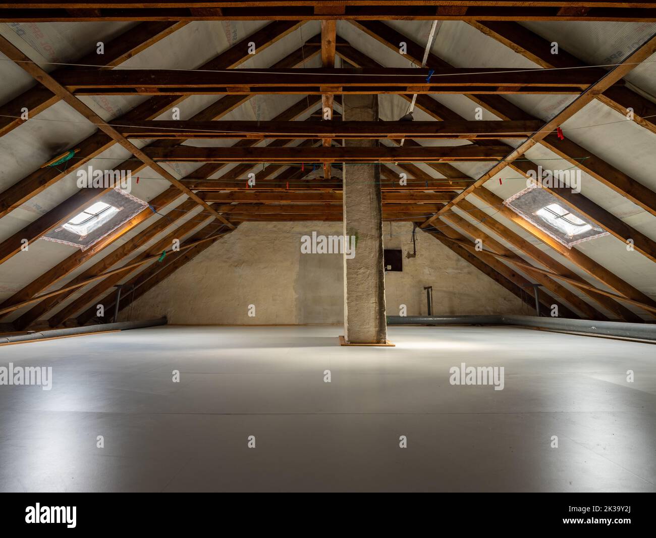 Grenier symétrique de forme triangulaire. Une chambre vide sous le toit avec une structure visible de planches en bois. L'espace est utilisé pour la ligne de lavage Banque D'Images