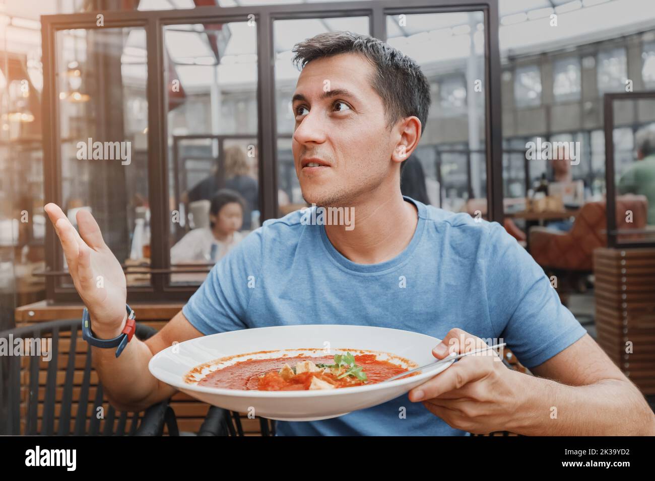 un client mécontent du restaurant se plaint de l'odeur dégoûtante d'un bol de soupe avec des ingrédients gâtés et va se plaindre au Banque D'Images