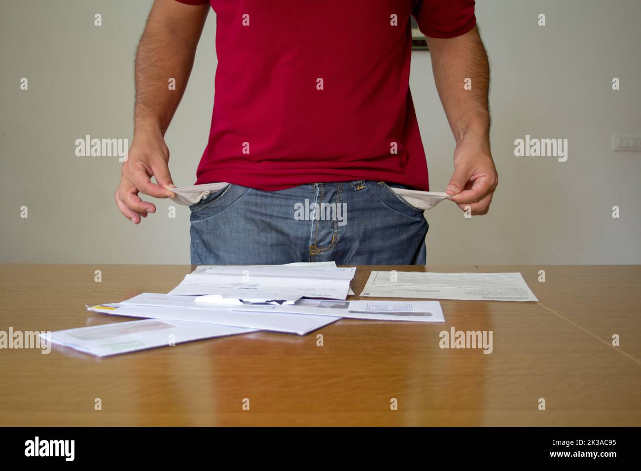 homme avec ses poches à pantalon tourné à l'intérieur devant quelques factures d'électricité et de gaz. augmentation du coût des factures en raison de la crise mondiale Banque D'Images