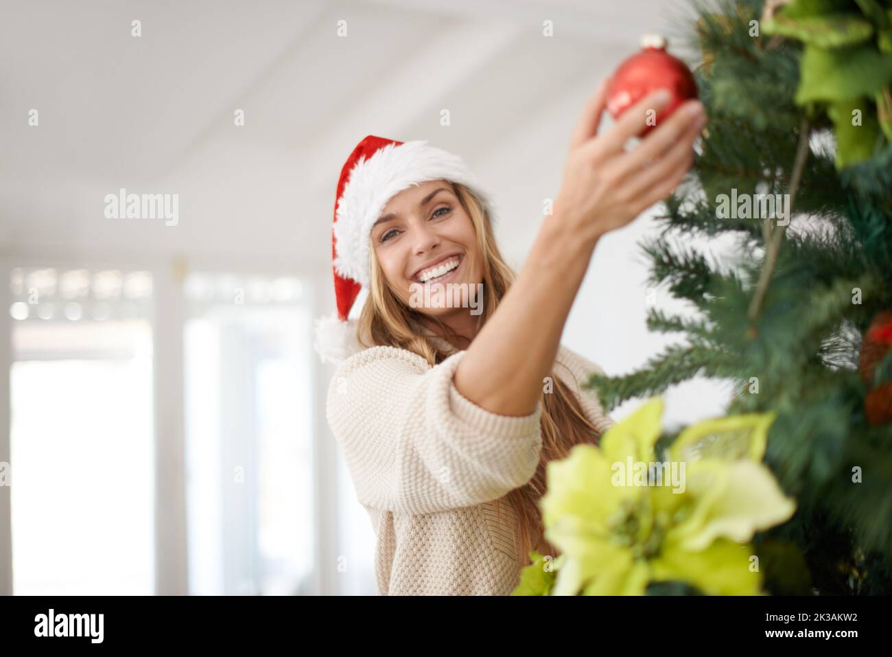 Entrer dans l'esprit de Noël. Une femme attrayante décorant son arbre de noël pendant qu'elle est à la maison. Banque D'Images