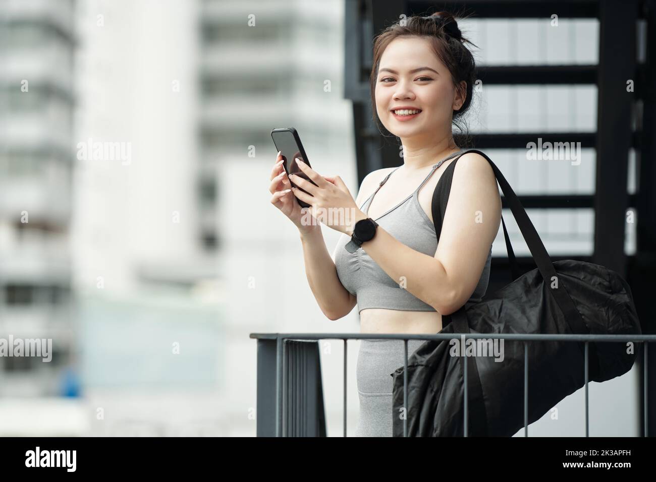 Collage numérique photo réaliste d'une athlète féminine debout sur un balcon et envoyant un message texte à son entraîneur de fitness Banque D'Images