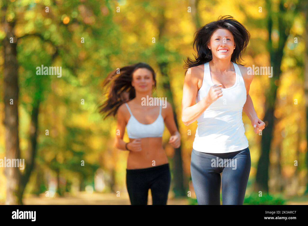 Seulement une foulée derrière. Deux femmes jogging ensemble dans un parc en automne. Banque D'Images