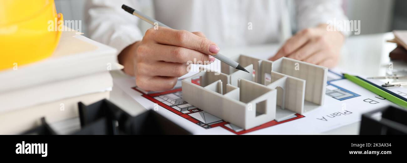 Femme designer montrant 3D modèle de maison en studio fermé Banque D'Images