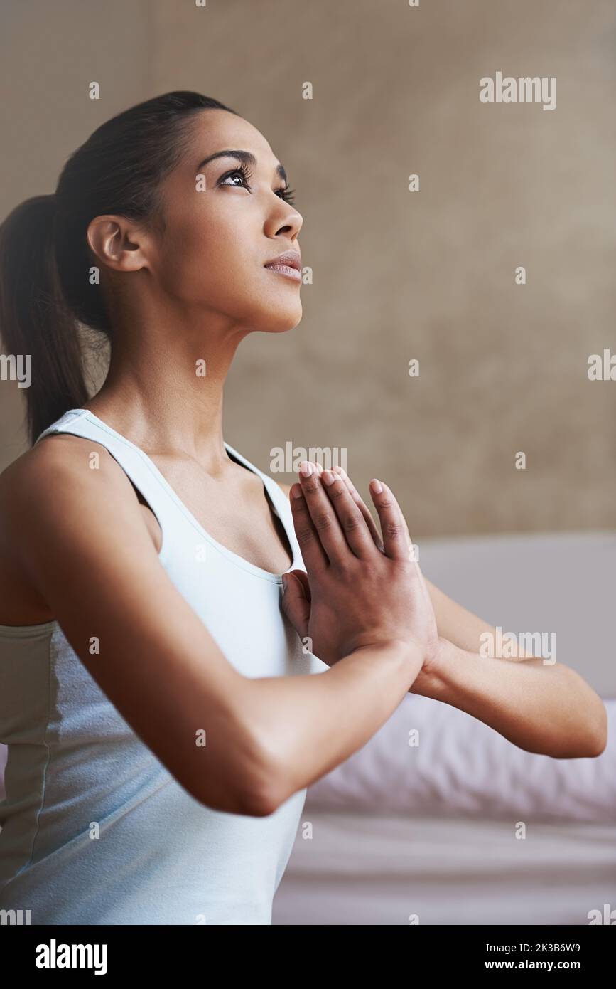 Prendre le temps de trouver la paix. Une jeune femme faisant du yoga à la maison. Banque D'Images
