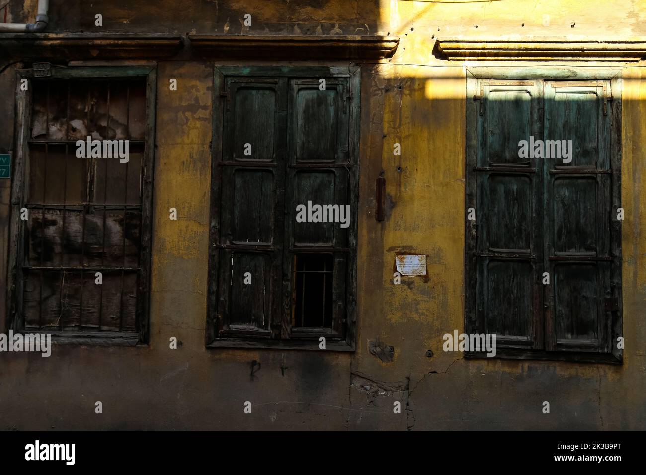 Les anciennes fenêtres et la façade jaune grungy d'une maison libanaise abandonnée Banque D'Images