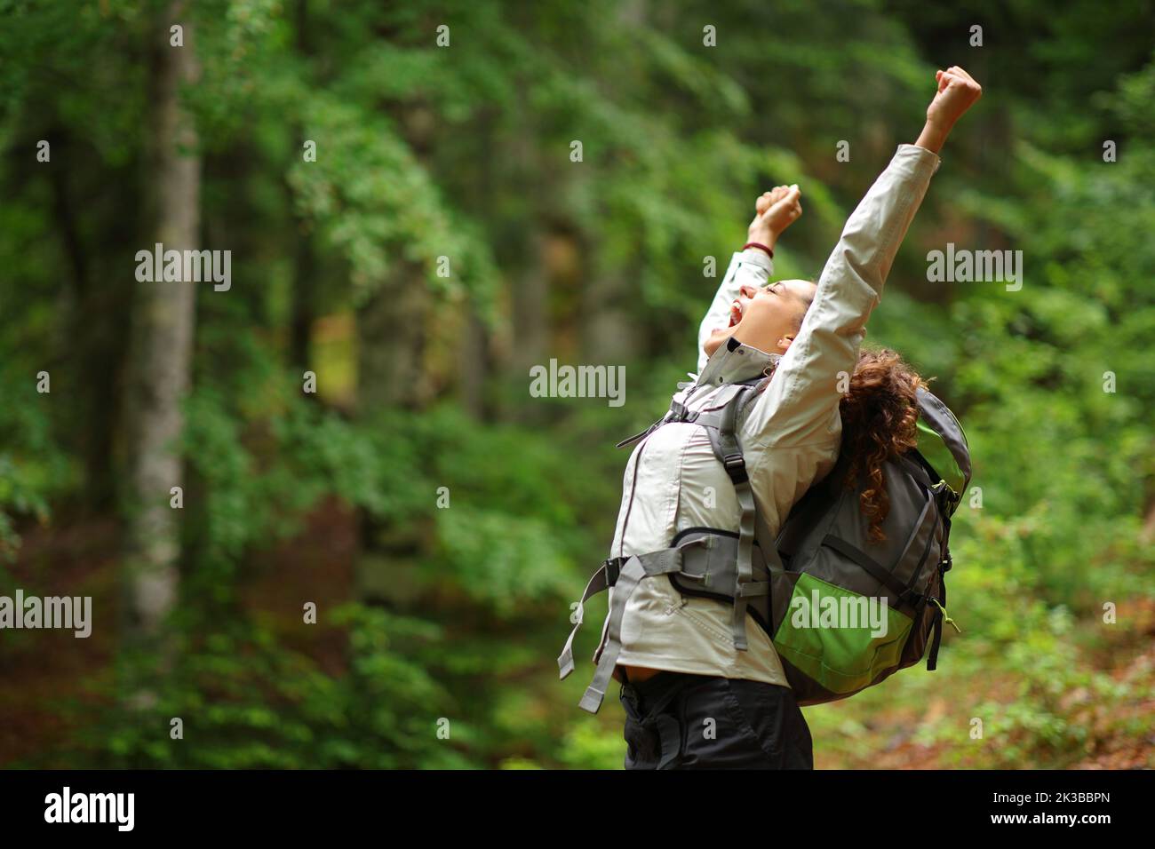 Randonneur enthousiaste levant des armes célébrant des vacances dans une forêt Banque D'Images