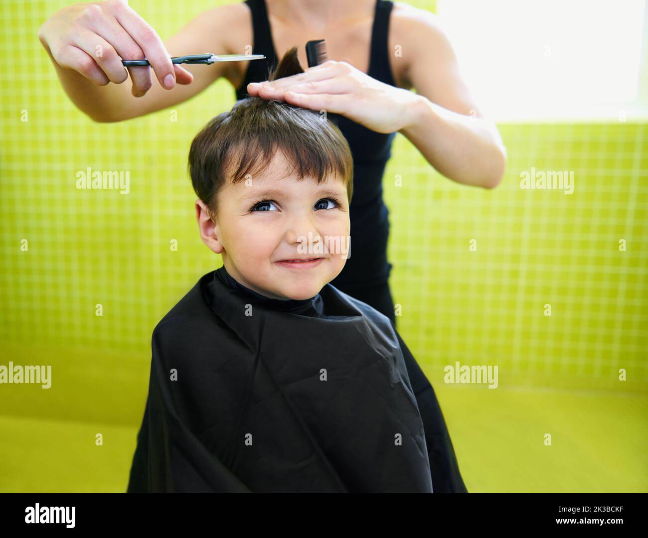 Pourquoi ai-je même besoin d'une coupe de cheveux. Un jeune garçon obtient sa première coupe de cheveux. Banque D'Images