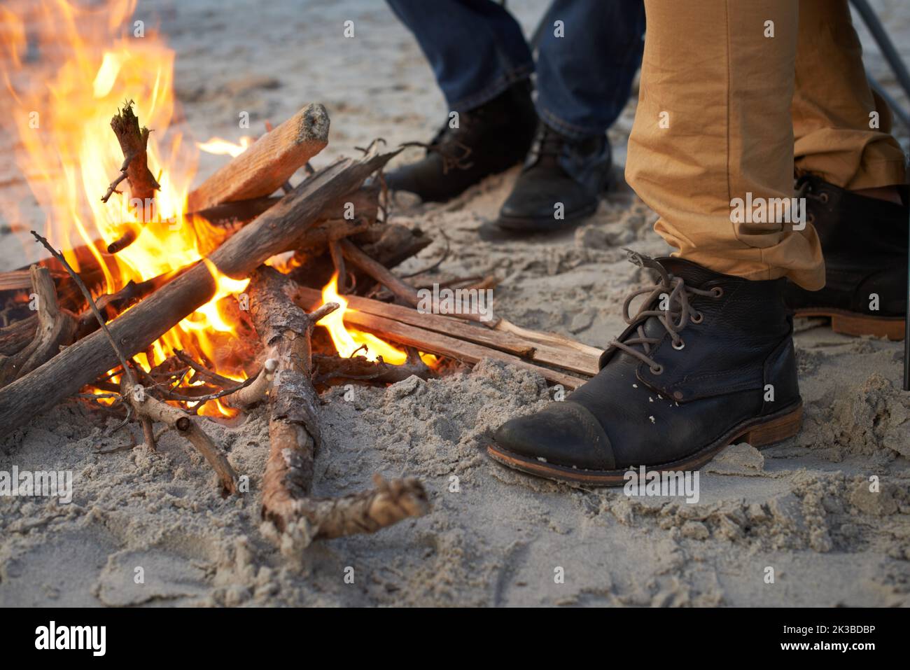 C'était une nuit froide. Deux jeunes hommes assis autour d'un feu sur la plage. Banque D'Images