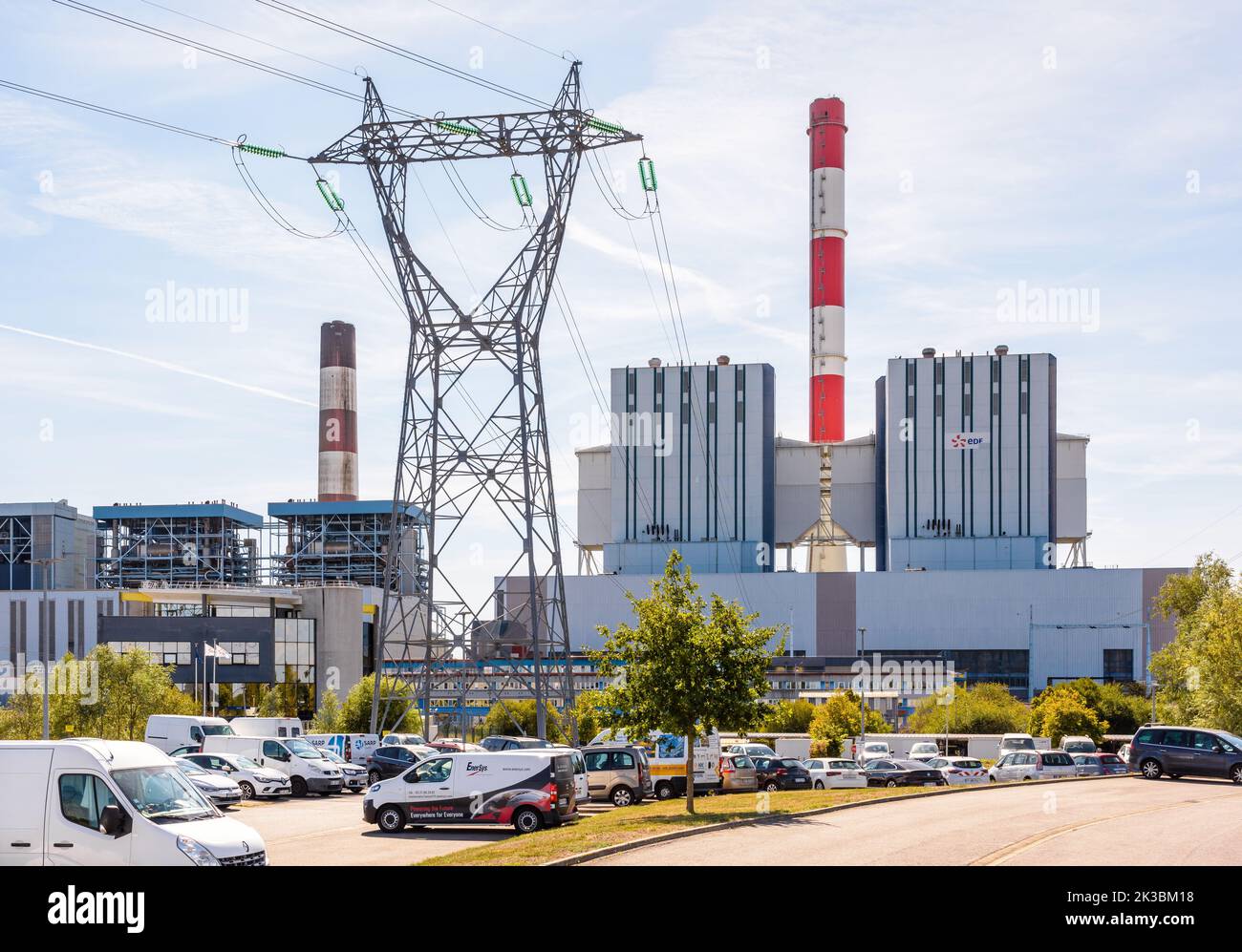Bâtiment principal de la centrale au charbon EDF de Cordemais près de Nantes, France, avec un pylône électrique et un parking par beau temps d'été. Banque D'Images