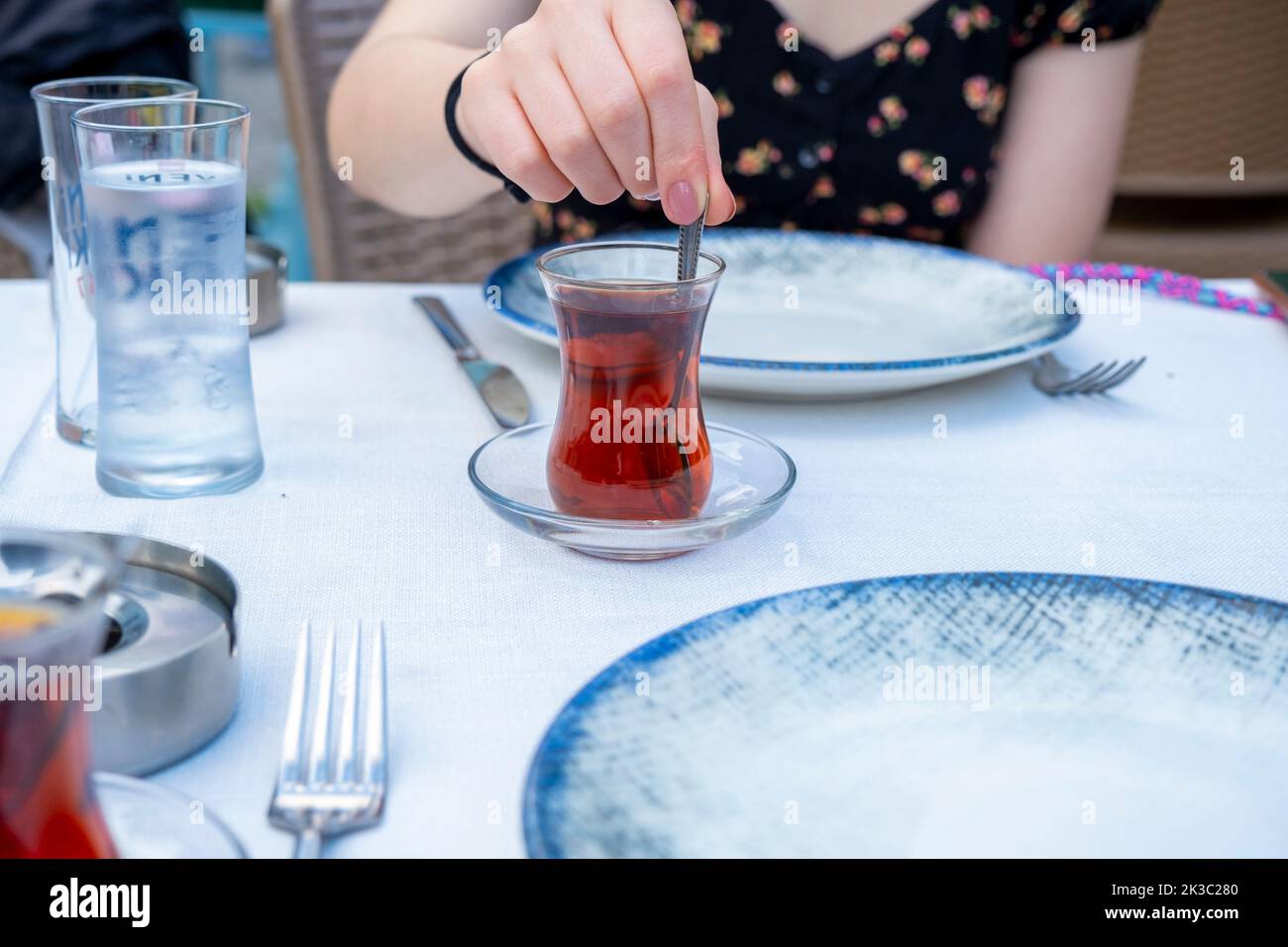 Femme mélangeant à la main le thé turc traditionnel, raki turc sur l'arrière-plan, dinde pub et le concept de boisson raki, salon vue, idée de boisson turque Banque D'Images